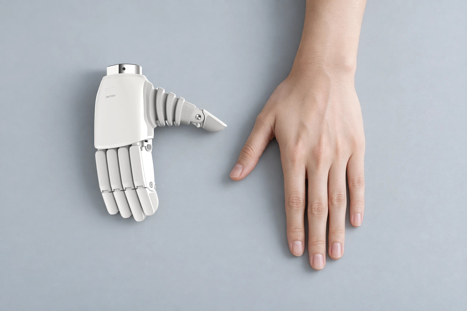 Complete small Lite-S hand beside a larger full adult hand on the same tabletop plane